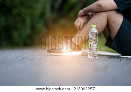 Young tired man having a rest after jogging outdoors summer time. Healthy lifestyle concept