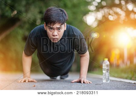 Fitness Man doing push-ups during outdoor cross training workout. Beautiful young and fit fitness sport model training outside in fall.