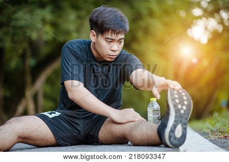 Sporty man stretching and warming up legs for running fitness  workout. Sport and healthy lifestyle concept. Man exercising outside.