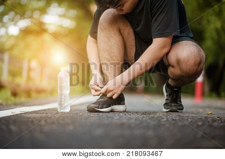 run runner with water and sport shoe road jogging flare sunset asphalt street fitness cross sunbeam success running sportswear.Man tying jogging shoes.A person running outdoors on a sunny day.