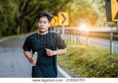 Active healthy runner jogging outdoor. Dinking water.