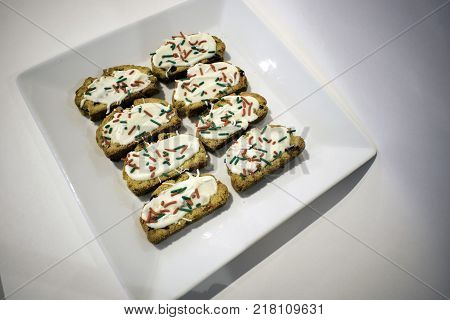Eight decorated cookies served on a square white plate on white surface