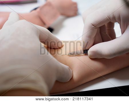 A physician wearing latex gloves performs an intradermal injection at a pediatric patient's forearm. Healthcare and vaccination concept.