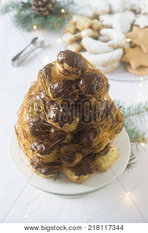 Crockembush cake and Christmas cookies in a Christmas decoration with a garland of fir branches and cones. Selective focus.