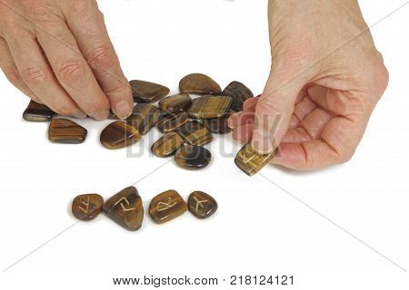 Giving a Runestone Reading - Pile of rune stones and a pair of hands picking out upturned stones isolated on a white background