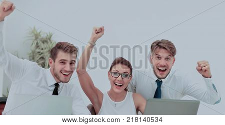 Team of three work colleagues with their arms raised in celebrat