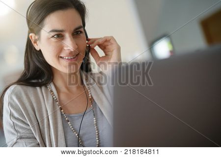 Home-office teleoperator talking on phone with headset