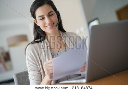 Home-office teleoperator talking on phone with headset