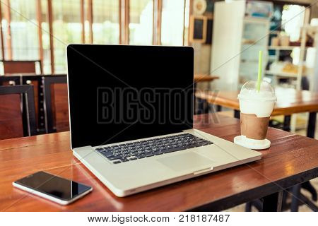 Laptop computer black screen on wood table in coffee shop.  Laptop on table. Laptop on vintage tone. Laptop in cafe. Laptop and smartphone on wood table.