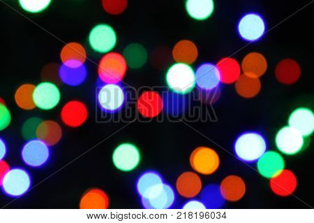 Celebration atmosphere. Bokeh of multicolored highlights on a black background.