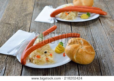 German street food: Hot Debreziner sausages  with sauerkraut, spicy mustard and a fresh roll served on a paper plate