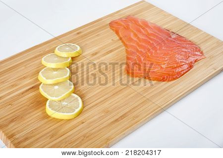 Smoked Fillet trout with lemon on a cutting board. Seafood.