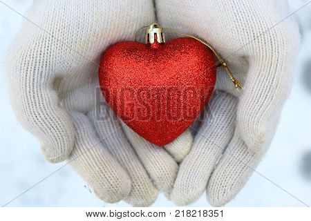 A heart in the arms. White mittens and heart. Heart on the snow. The spirit of Christmas. Christmas traditions. Winter mood. Valentine's day. Love and feelings. Red heart