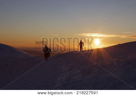 Winter sunset on Pen y Fan mountain in the Brecon Beacons National Park, UK with silhouettes of unrecognisable  climbers and a winter skies background.
