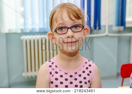 Portrait of sweet little girl with glasses and carefree expression on her face.
