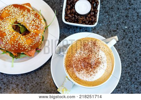 Fresh bagel with salad and smodel fish salmon and cup of coffee. Breakfast in a cafe or restaurant. Healthy food.
