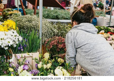 A small business for selling flowers. Street shop. A young girl is a salesman doing work. There are different kinds of flowers on the counter