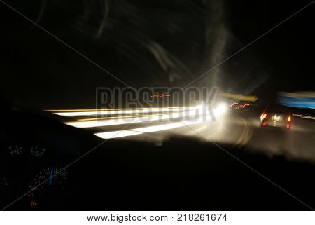 Using a long exposure to capture a night time driving experience while showcasing motion blurr on the highway and a focused interior of the drivers vehicle.