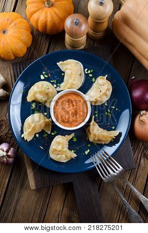 Typical Nepalese meal momo. Crescent shape steam dumplings with curry sauce served with pumpkins on rustic background above view