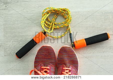 Jumping rope and sneakers on wooden background