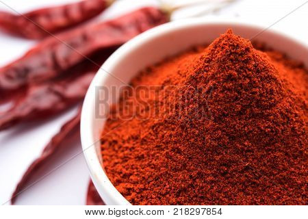 Red Chilly Powder in a bowl with dried red chillies over colourful background or pile of red chilli powder over plain background