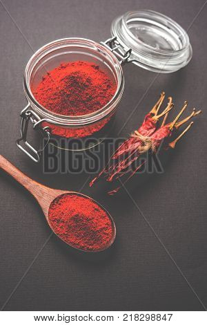 Red Chilly Powder in a bowl with dried red chillies over colourful background or pile of red chilli powder over plain background