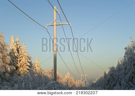 snow-covered glade on top of the hill surrounded by frost-covered trees in clear frosty weather