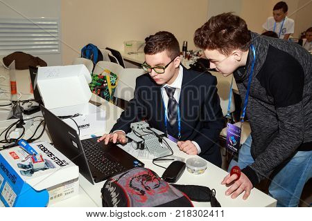 MOSCOW/ RUSSIA - DECEMBER 13, 2017. Two school boys with laptop, programming the robot at robotics competitions.