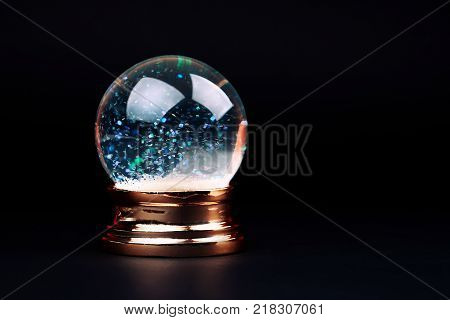 Beautiful snow ball with snowfall inside over black background.