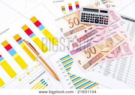 Foglio grafico e dati finanziario. Denaro brasiliano e penna.