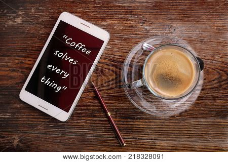Inspirational motivating quote about coffee on smartphone and cup of coffee.