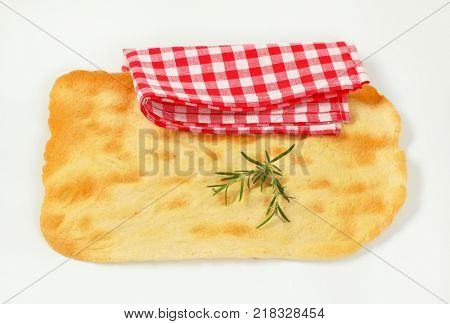 piece of traditional Tuscan flatbread (Ghiottina Toscana) and checkered place mat on white background