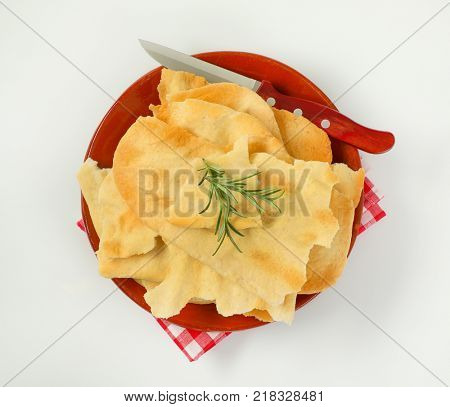 pieces of traditional Tuscan flatbread (Ghiottina Toscana) and kitchen knife on brown plate