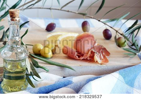 Still life with Spanish a jamon, olives and olive oil in a bottle on a wooden cutting board