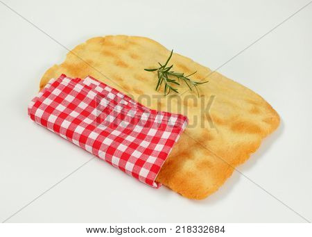 piece of traditional Tuscan flatbread (Ghiottina Toscana) and checkered place mat on white background