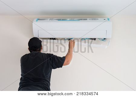 Man worker installs indoor air conditioner in the new home. Select focus