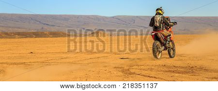 Ait Saoun Morocco - February 22 2016: panoramic rare view of man in helmet riding bike in Ait Saoun desert of Morocco.