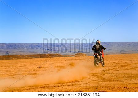 Ait Saoun Morocco - February 22 2016: Rare view of man in helmet riding bike in Ait Saoun desert of Morocco.