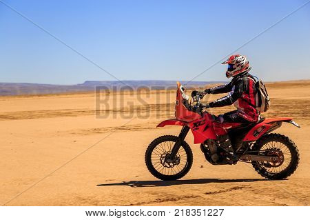 Ait Saoun Morocco - February 22 2016: side view of man in helmet riding bike in Ait Saoun desert of Morocco.