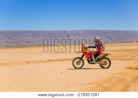 Ait Saoun Morocco - February 22 2016: side view of man in helmet riding bike in Ait Saoun desert of Morocco.