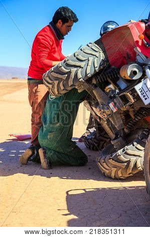 Ait Saoun Morocco - February 22 2016: Man with the help of mechanic trying to repair his car in the it Saoun desert of Morocco.