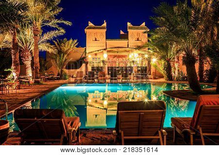 M'hamid Morocco - February 22 2016: view of pool bar in Chez le Pacha hotel with typical decoration with reflection in the poo and deck chairl in front