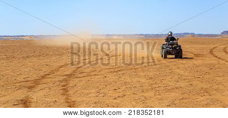 Ait Saoun Morocco - February 22 2016: panoramic view of man riding atv quad bike on sand in desert on a sunny day in Ait Saoun desert in Morocco.