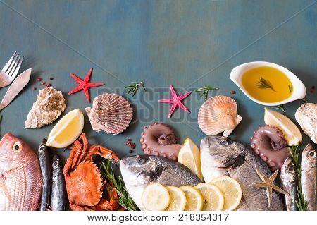 Appetizing fish and seafood on a blue background with copy space, fish knife and fork.