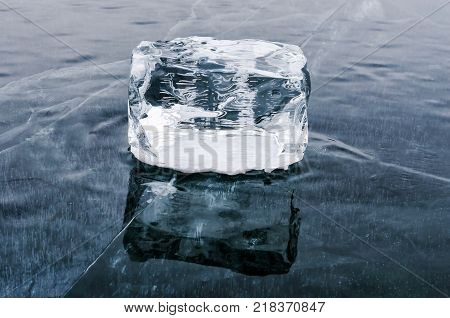 Single Ice Cube with reflection on the lake Baikal surface