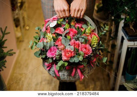 Womans hands holding a large wicker basket with beautiful flower composition for the Valentine day