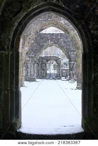 snow falling through a ruined okd church door in heptonstall in west yorkshire