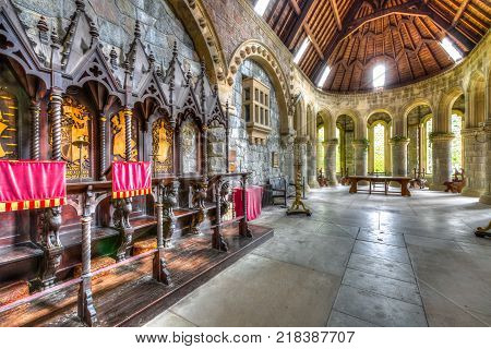 Argyll, Scottish highlands, United Kingdom - June 1, 2015: wooden chairs in the chancel hall of Saint Conan's Kirk gothic church. Marble colonnade and main altar on background.