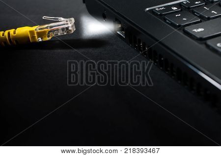 Yellow internet cable followes the light from the laptop