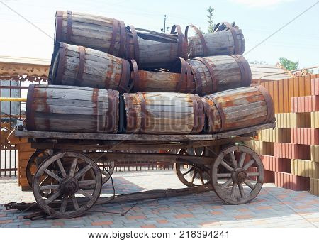 An old cart loaded with a lot of empty barrels that need repair.